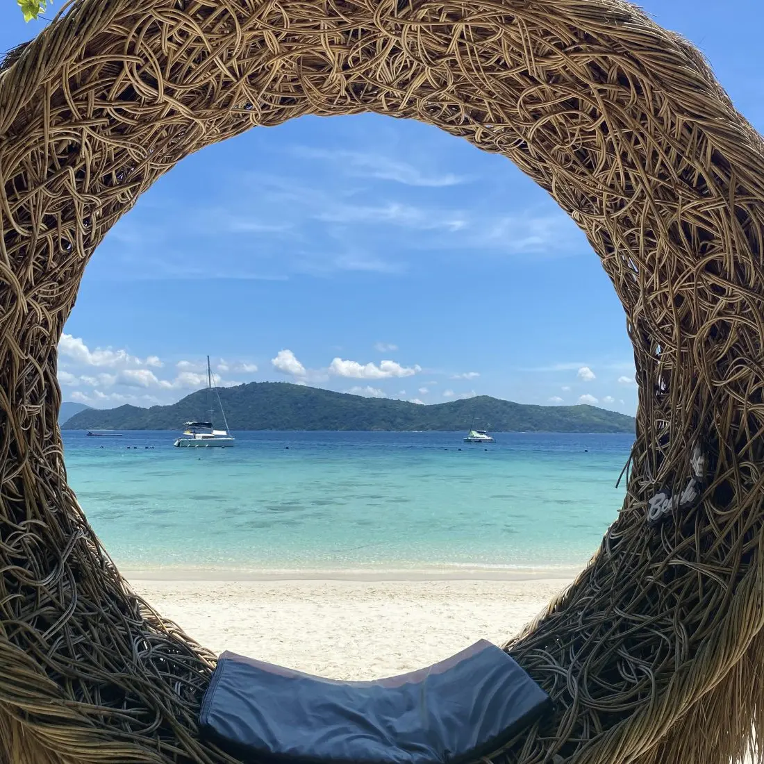 A beach and moored boats seen through a woven circular window