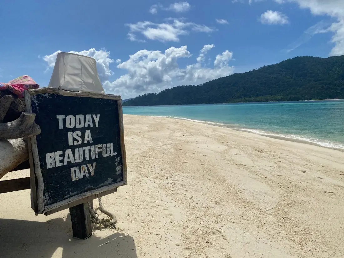 A vendor cart on the sand with a chalkboard sign