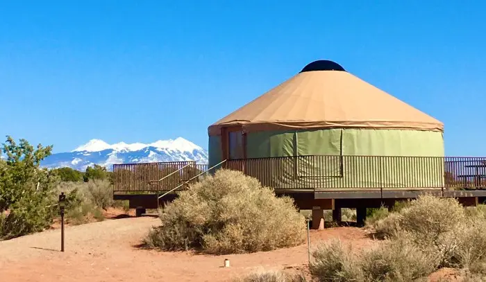 A yurt in the high desert with snow-capped mountains behind it