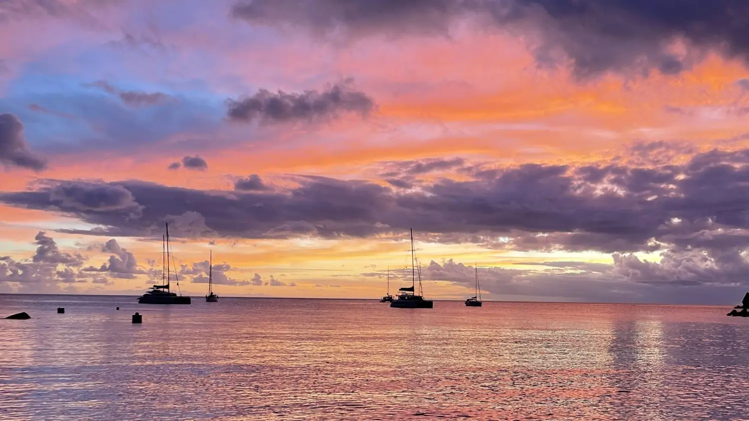 A sunset over a bay with boats at anchor