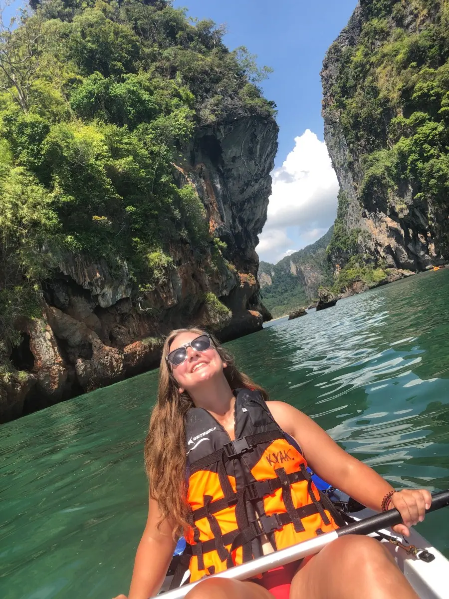 Sam Ray in a kayak beside a limestone cliff