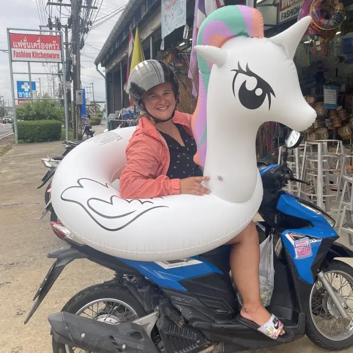 Sam on a scooter carrying an inflatable unicorn