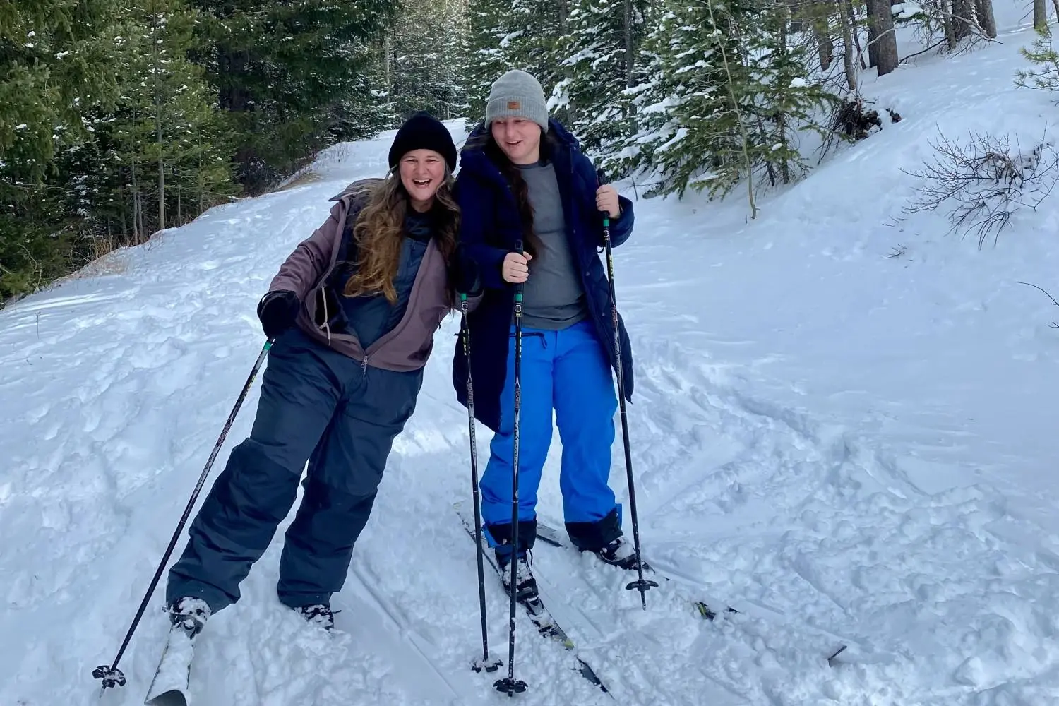 Mariya and Sam on cross-country skis on a snowy forest trail