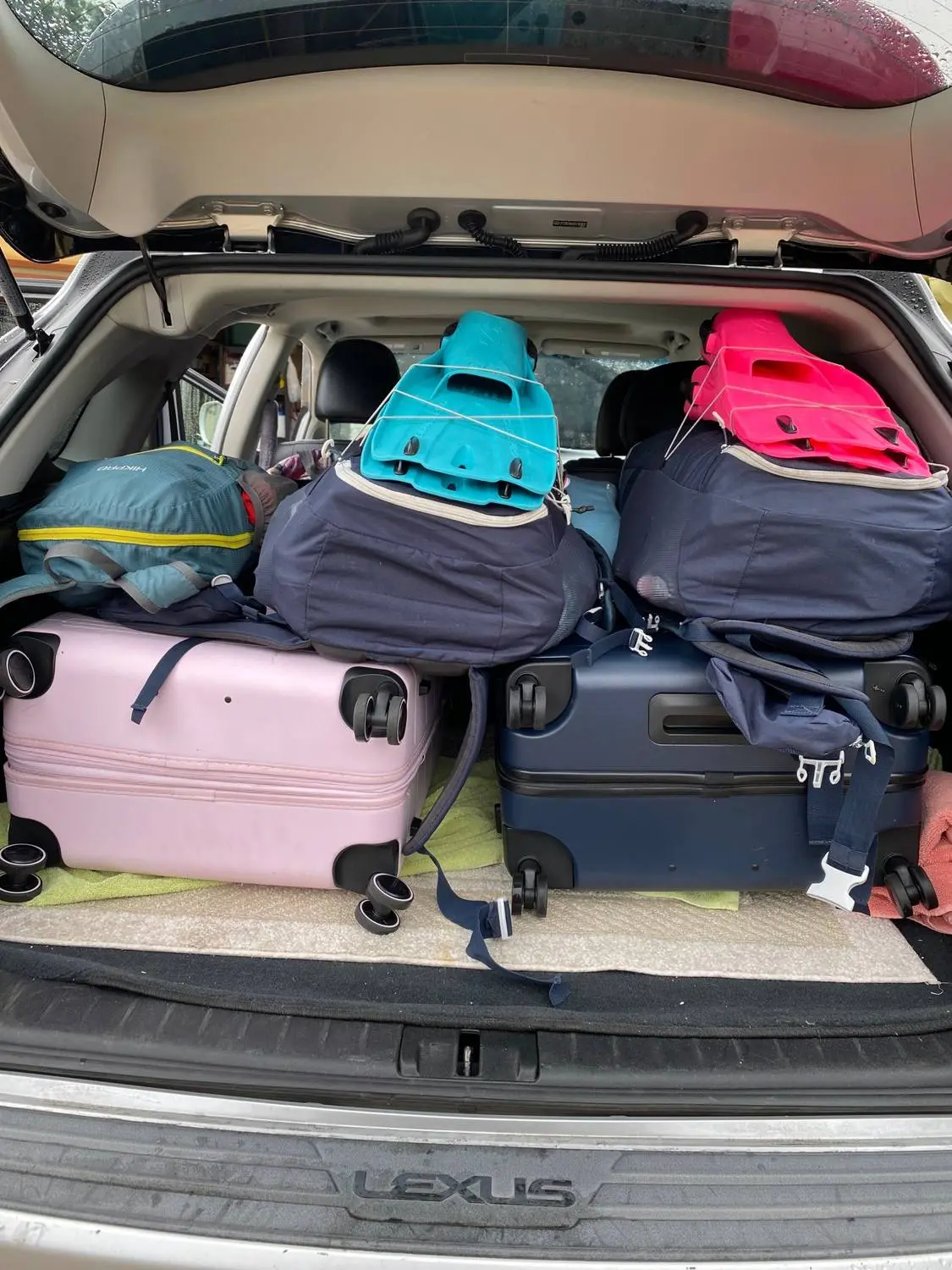 A car trunk packed with suitcases, backpacks and two pairs of dive fins