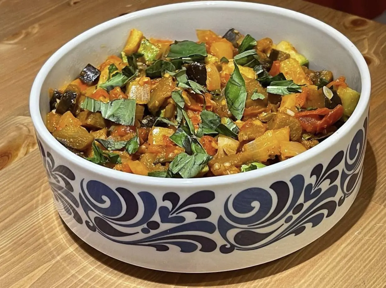 A bowl of home-cooked vegetable stew topped with fresh basil
