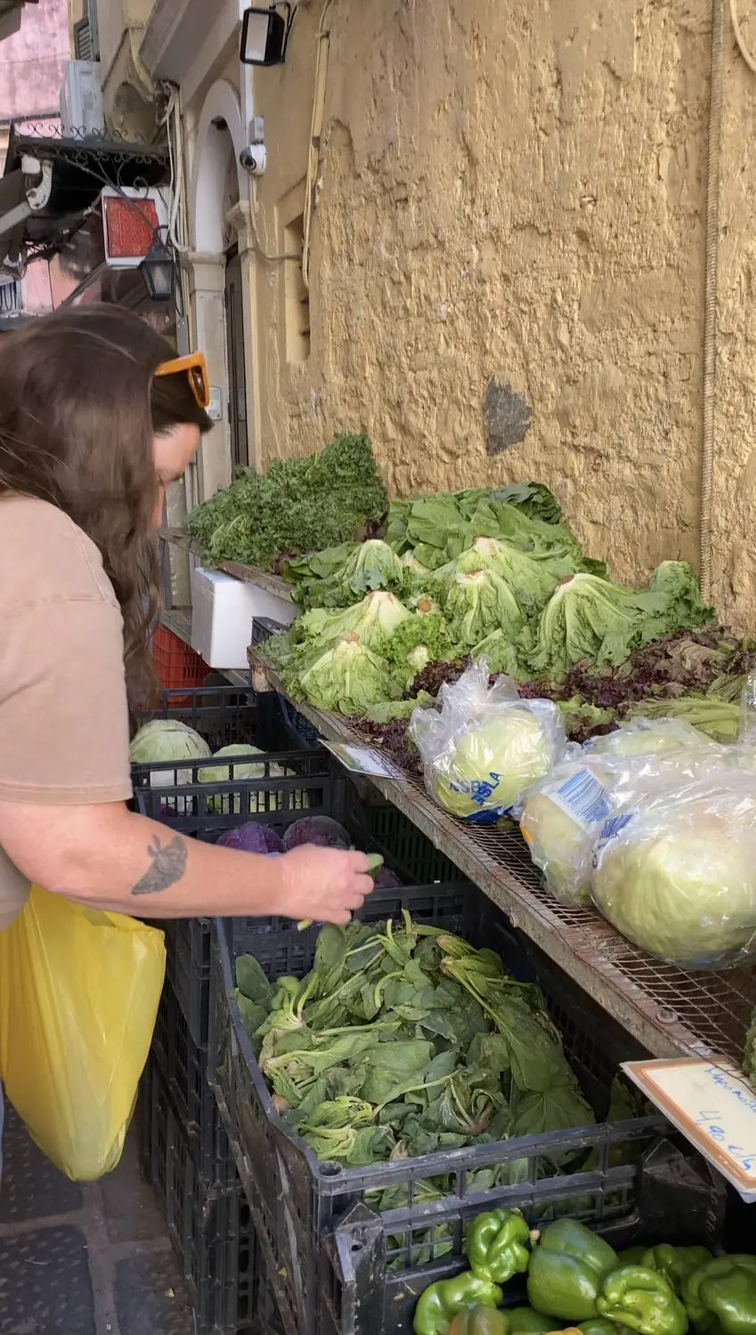 A woman choosing vegetables at a street market stall