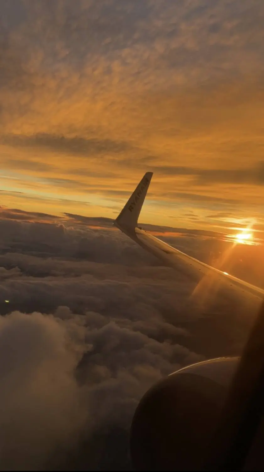 An airplane wing above the clouds at sunset