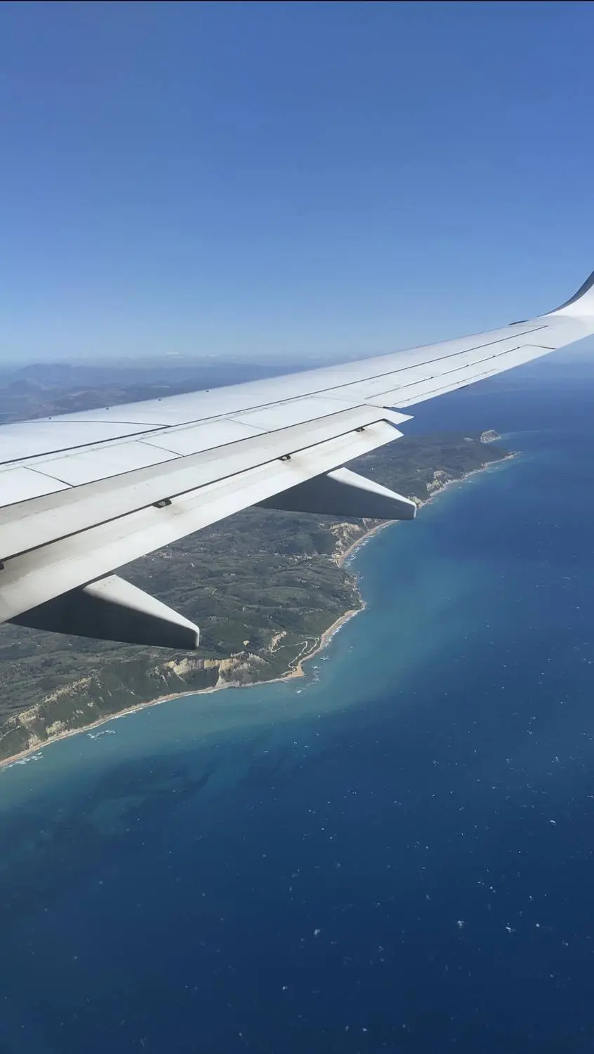 An airplane wing over a blue coastline